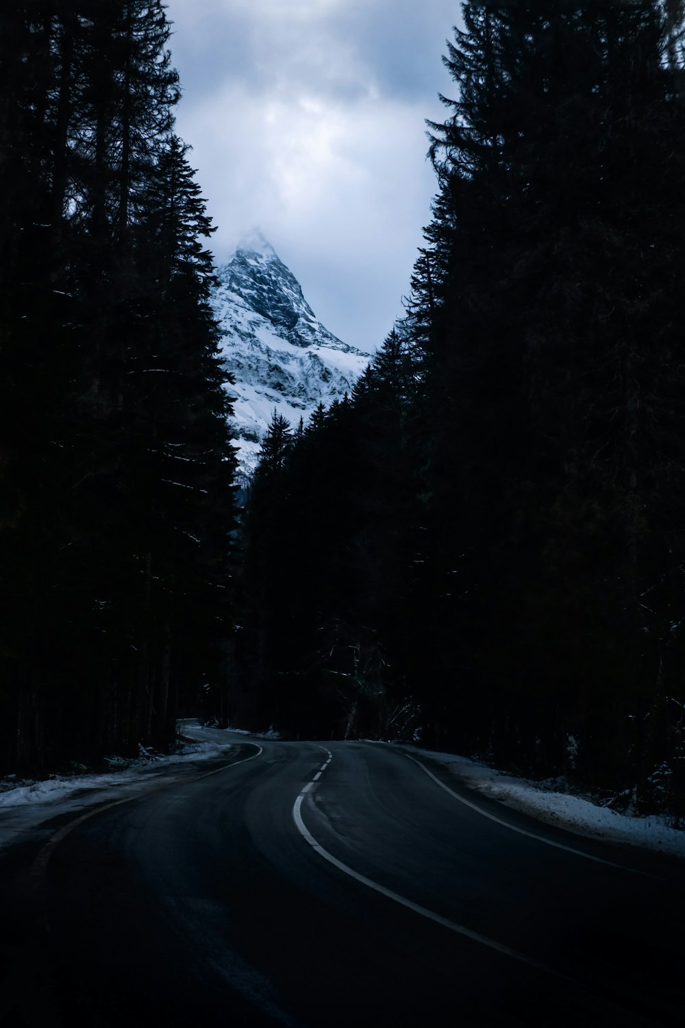 a road with a snow covered mountain in the background