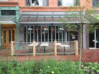A friendly small business owner chatting with customers outside their storefront on a sunny day.