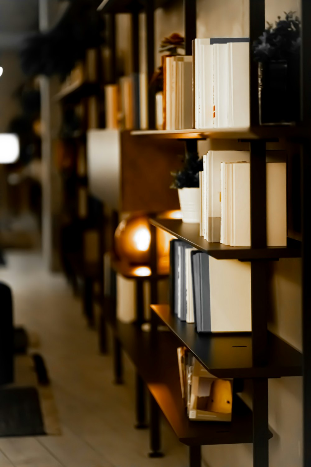 a bookshelf filled with lots of books next to a lamp