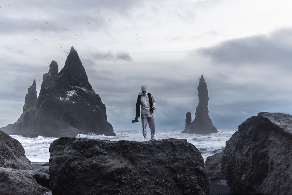 a man standing on rocks near the ocean