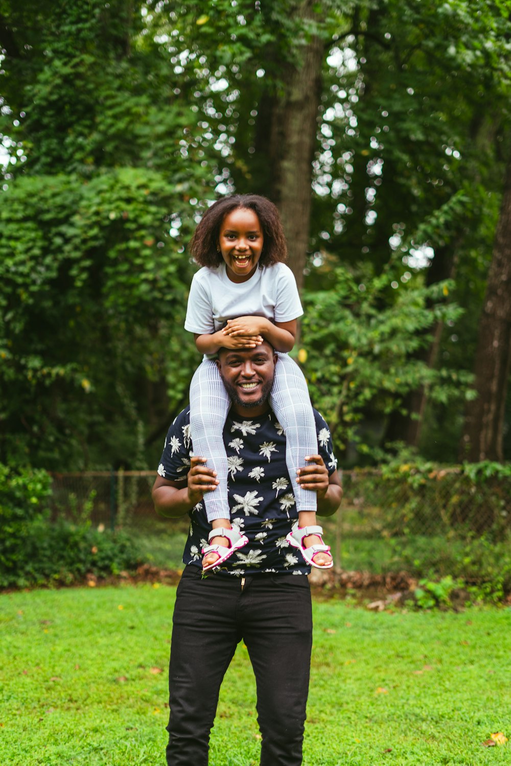 a man holding a little girl on his shoulders