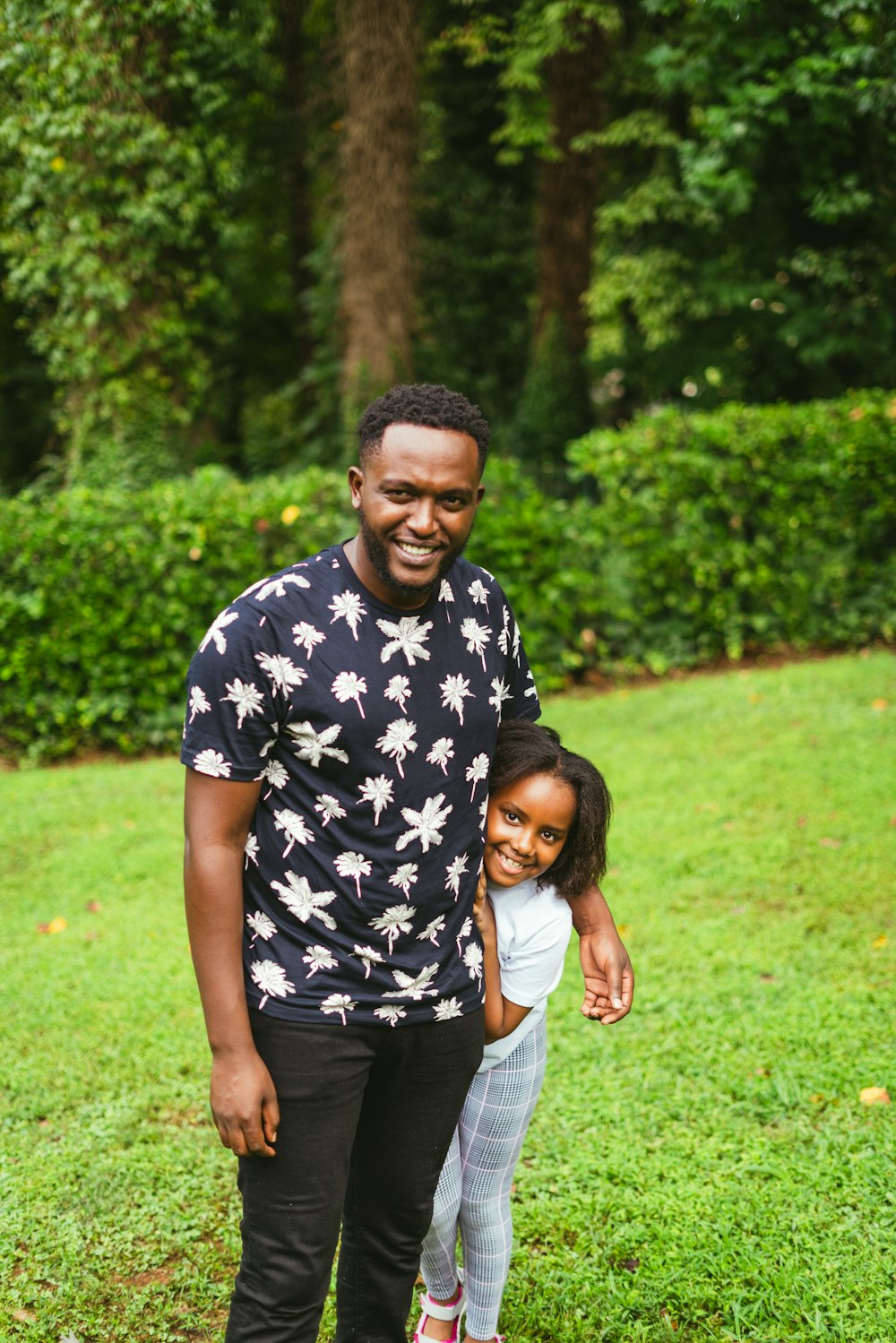 a man standing next to a little girl on a lush green field