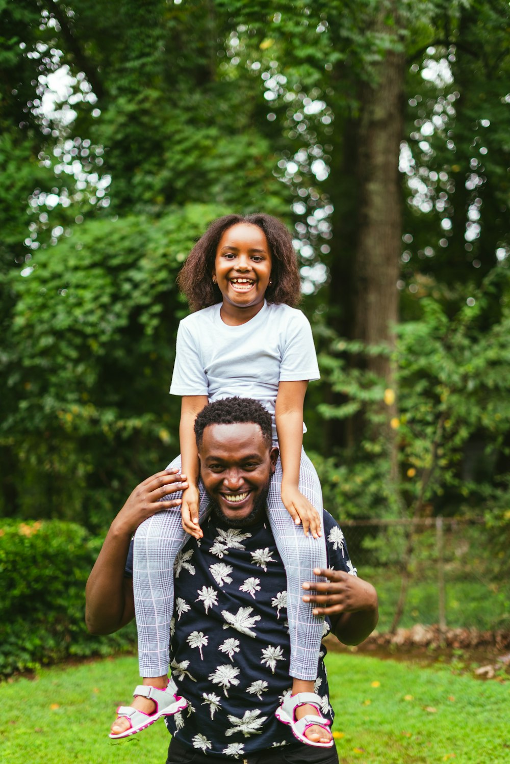 a man carrying a little girl on his shoulders