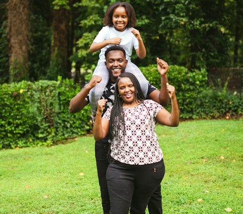 a man and two women holding a child on their shoulders