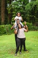 a man and two women holding a child on their shoulders