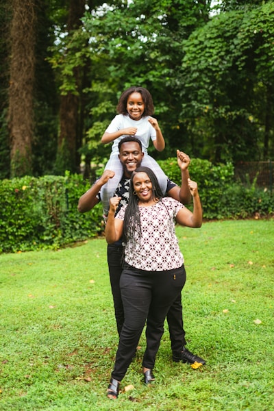a man and two women holding a child on their shoulders