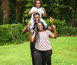 a man and two women holding a child on their shoulders