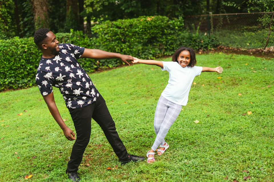 A dad spinning his daughter round on the grass