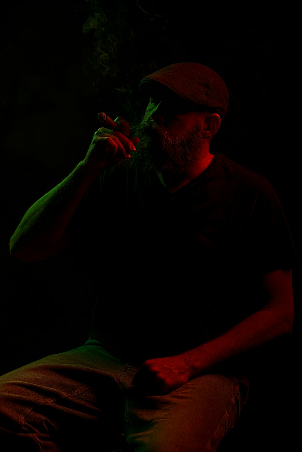 a man sitting in the dark smoking a cigarette