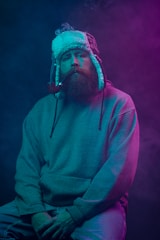 a man with a beard wearing a hat and smoking a cigarette