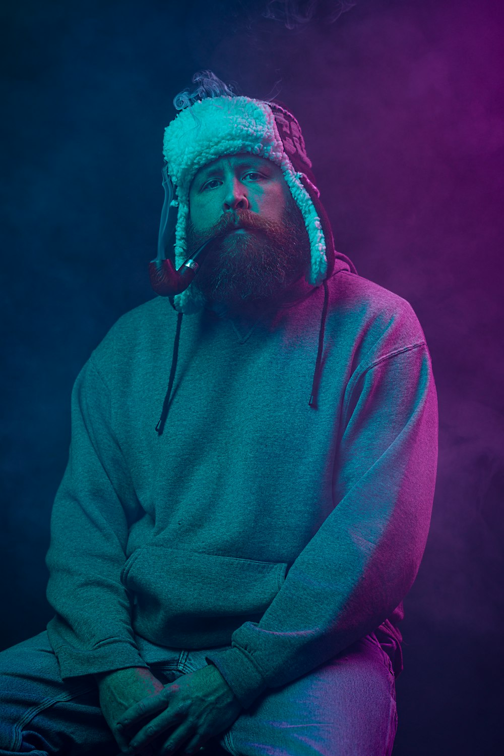 a man with a beard wearing a hat and smoking a cigarette