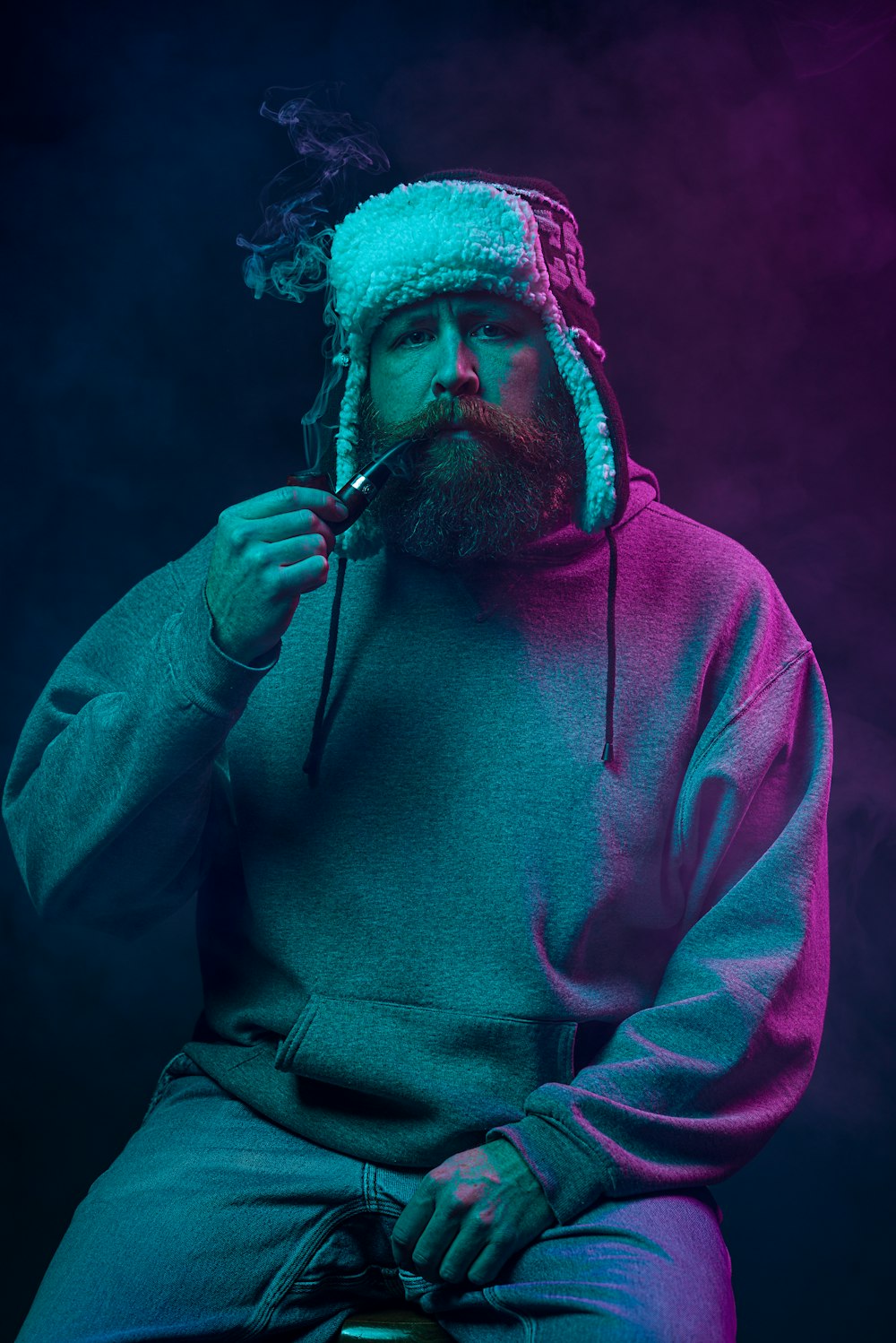 a man sitting on a stool with a pipe in his mouth