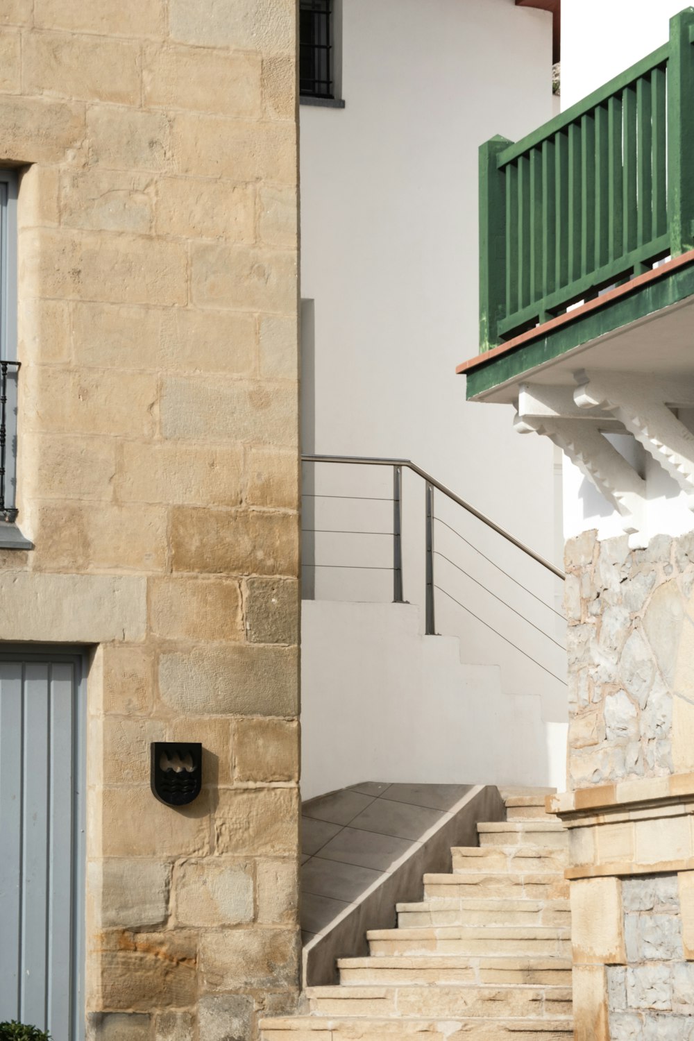 a stone building with a green balcony next to a set of stairs