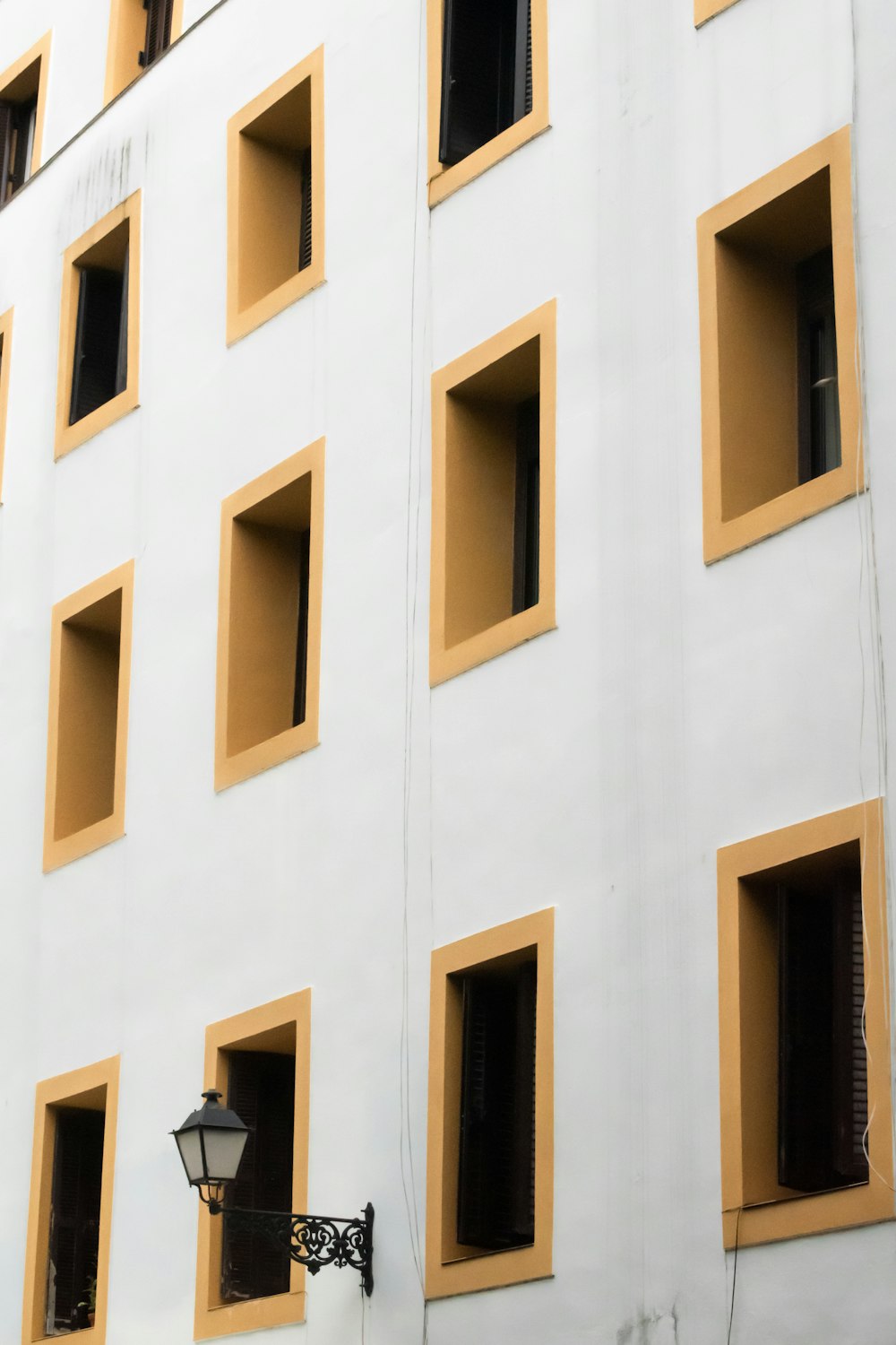 Un edificio bianco con finestre gialle e un lampione