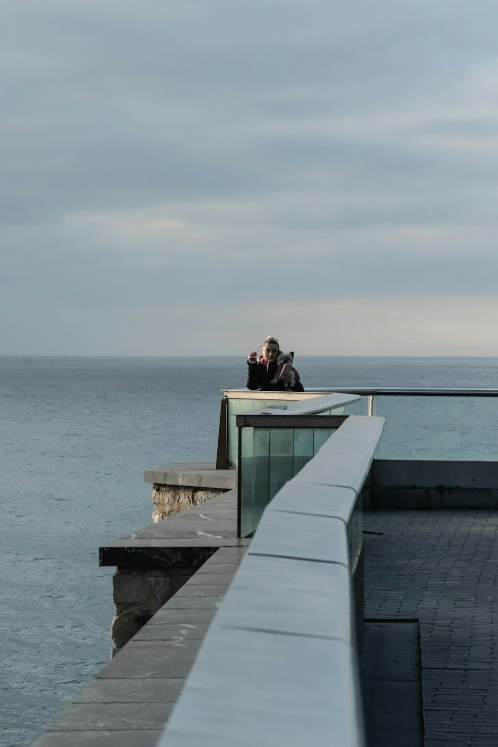 a couple of people sitting on top of a pier next to the ocean