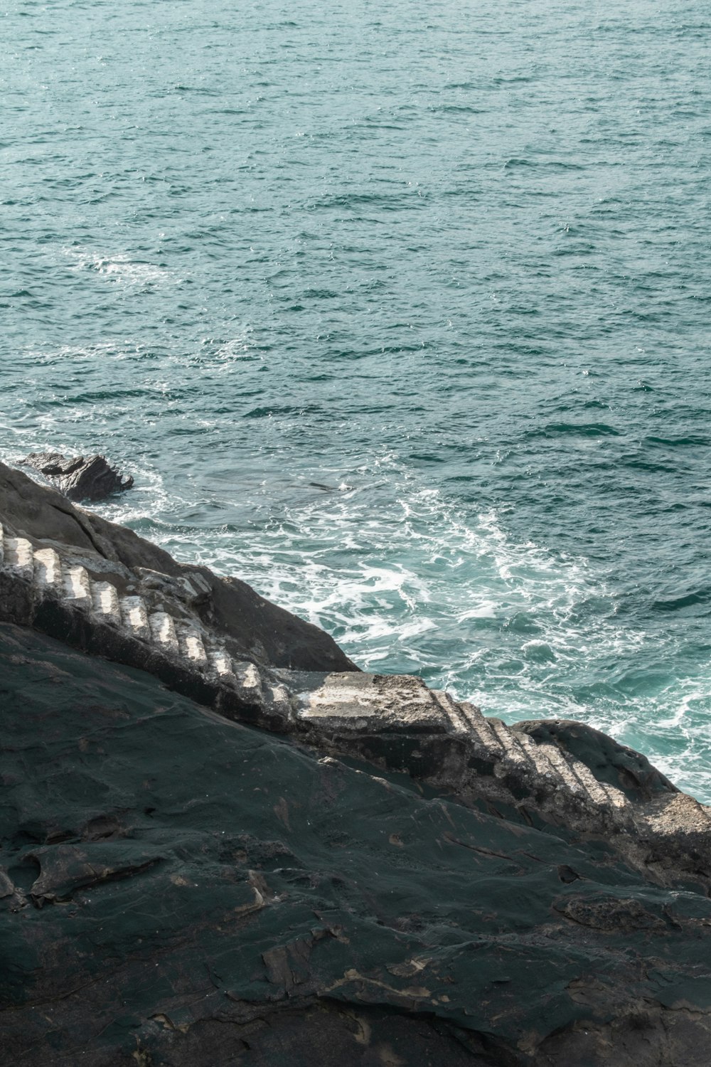 a person sitting on a rock next to the ocean