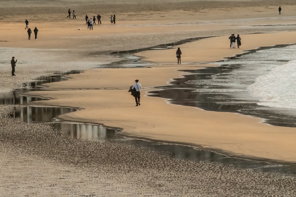 a group of people walking along a beach next to the ocean