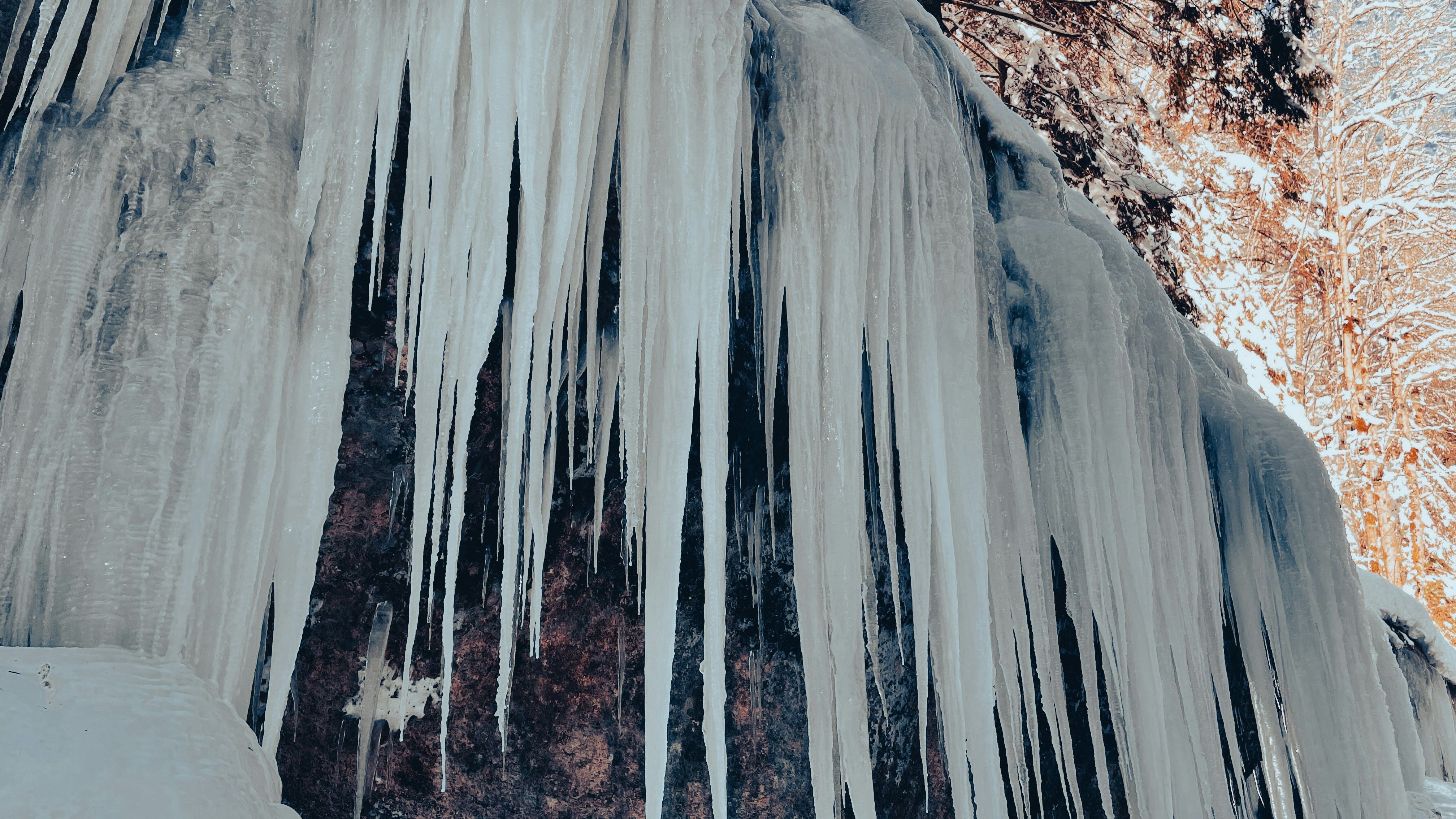 A frozen waterfall with icicles hanging off of it's sides photo – Free ...