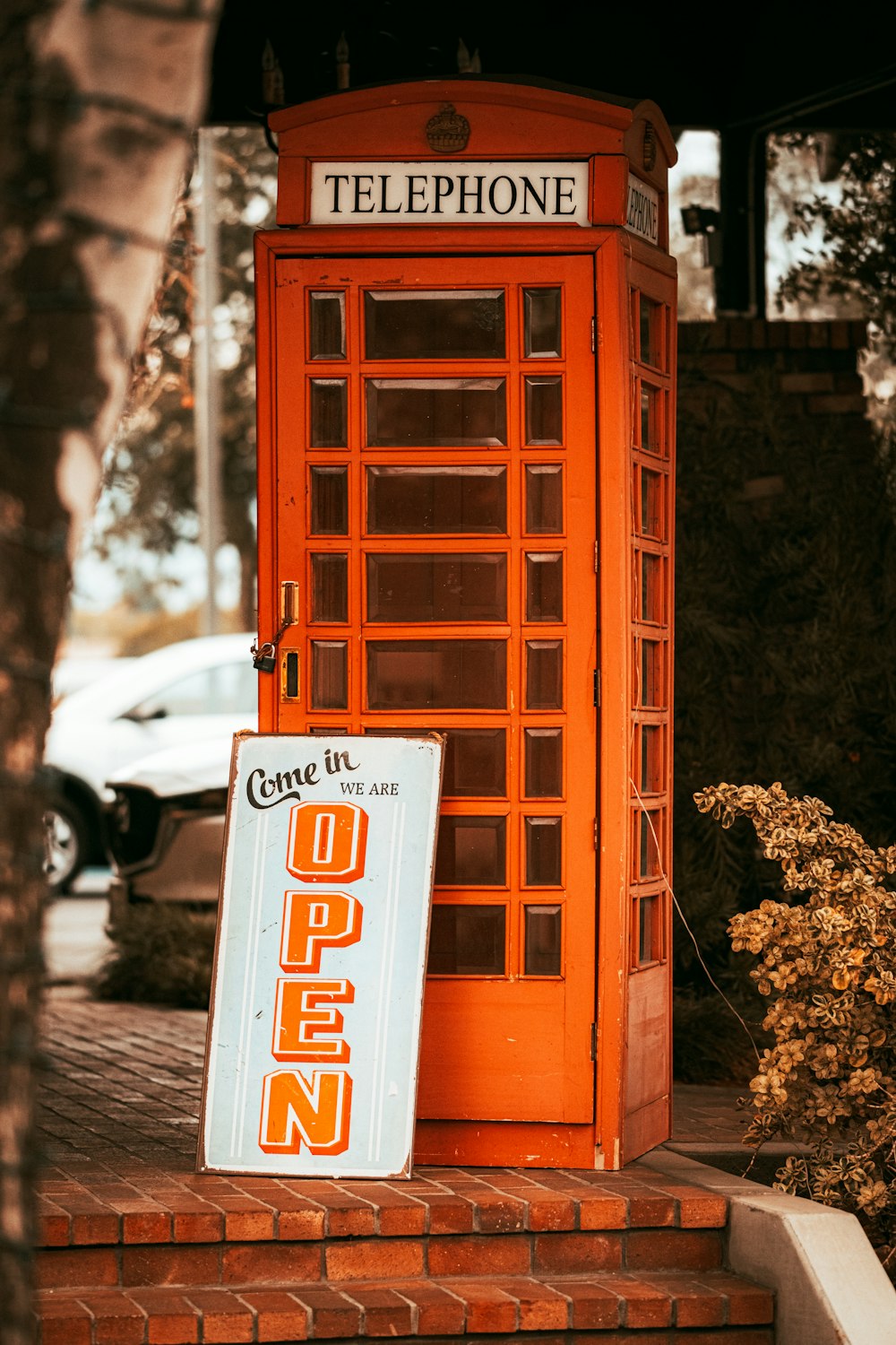 an orange telephone booth sitting on the side of a road