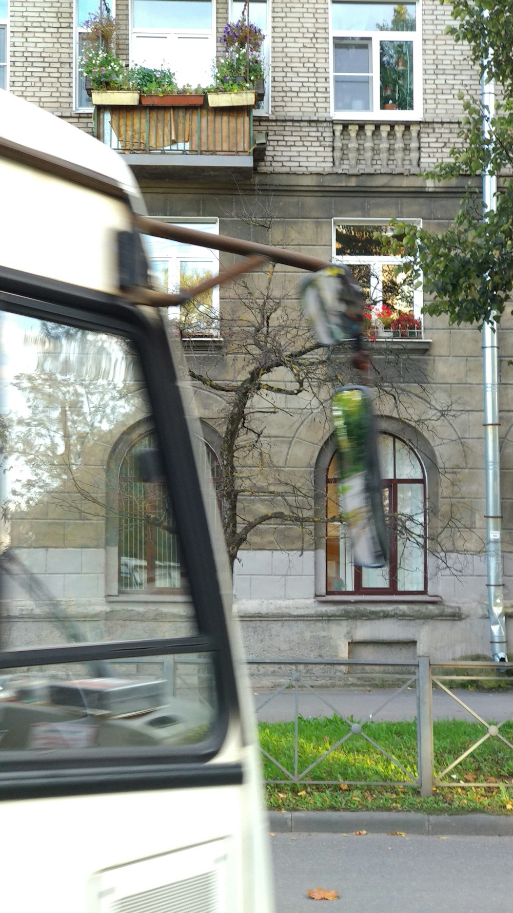 a white bus driving past a tall brick building