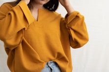 a woman in a yellow sweater is holding her head