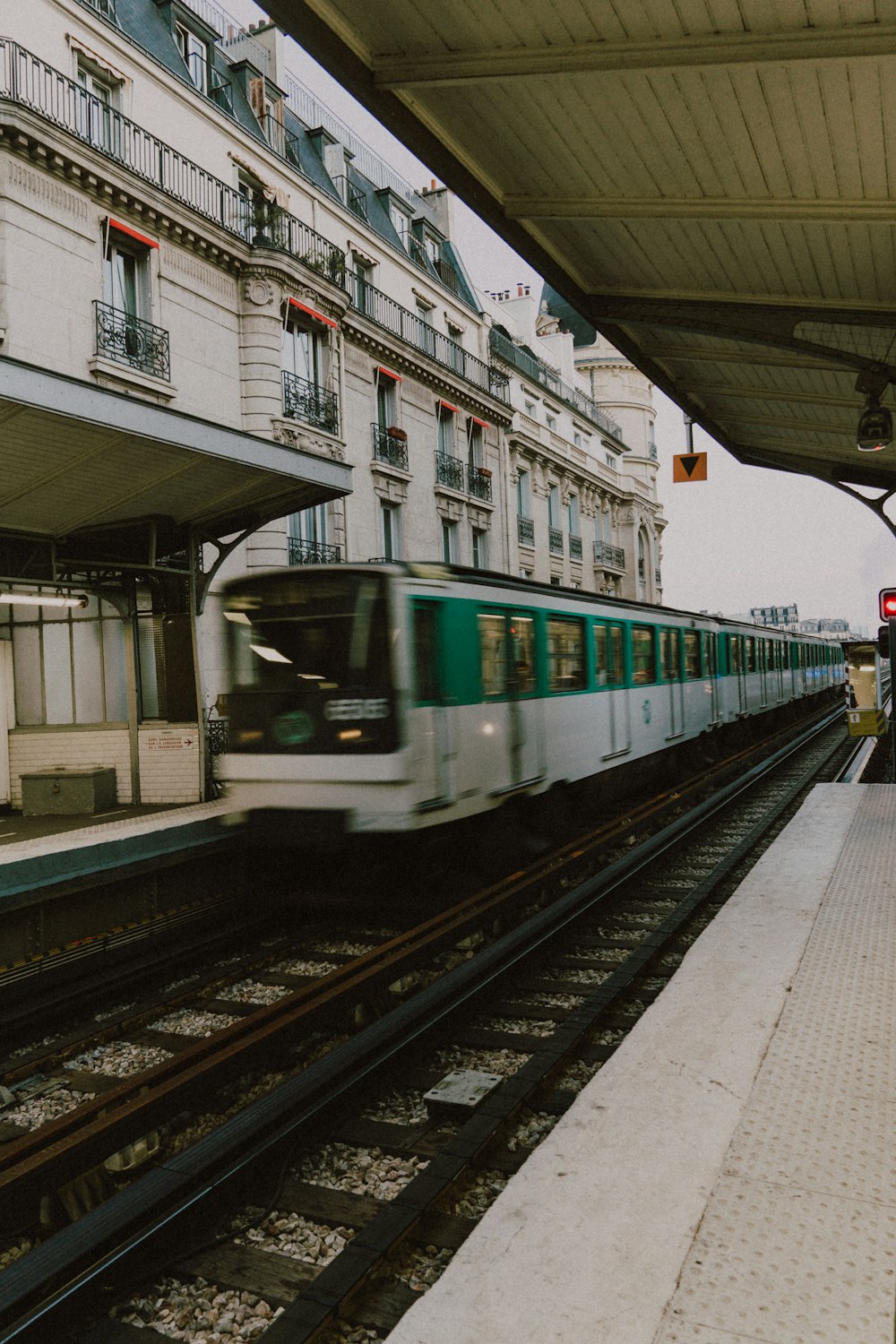 a train traveling past a tall building next to a train station