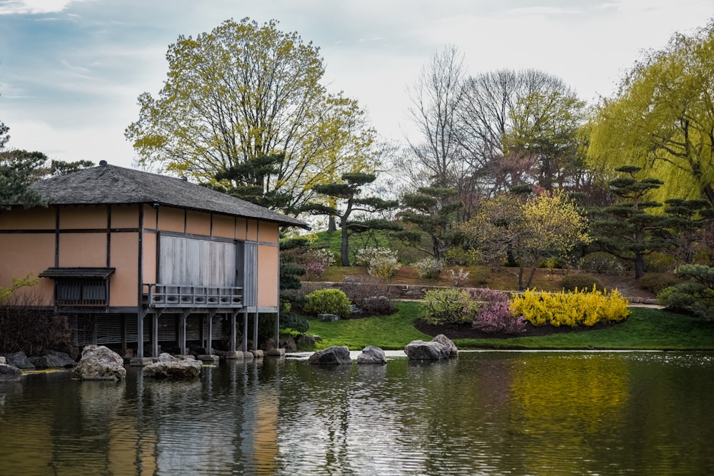 Una pequeña casa sentada en la cima de un lago junto a un exuberante bosque verde