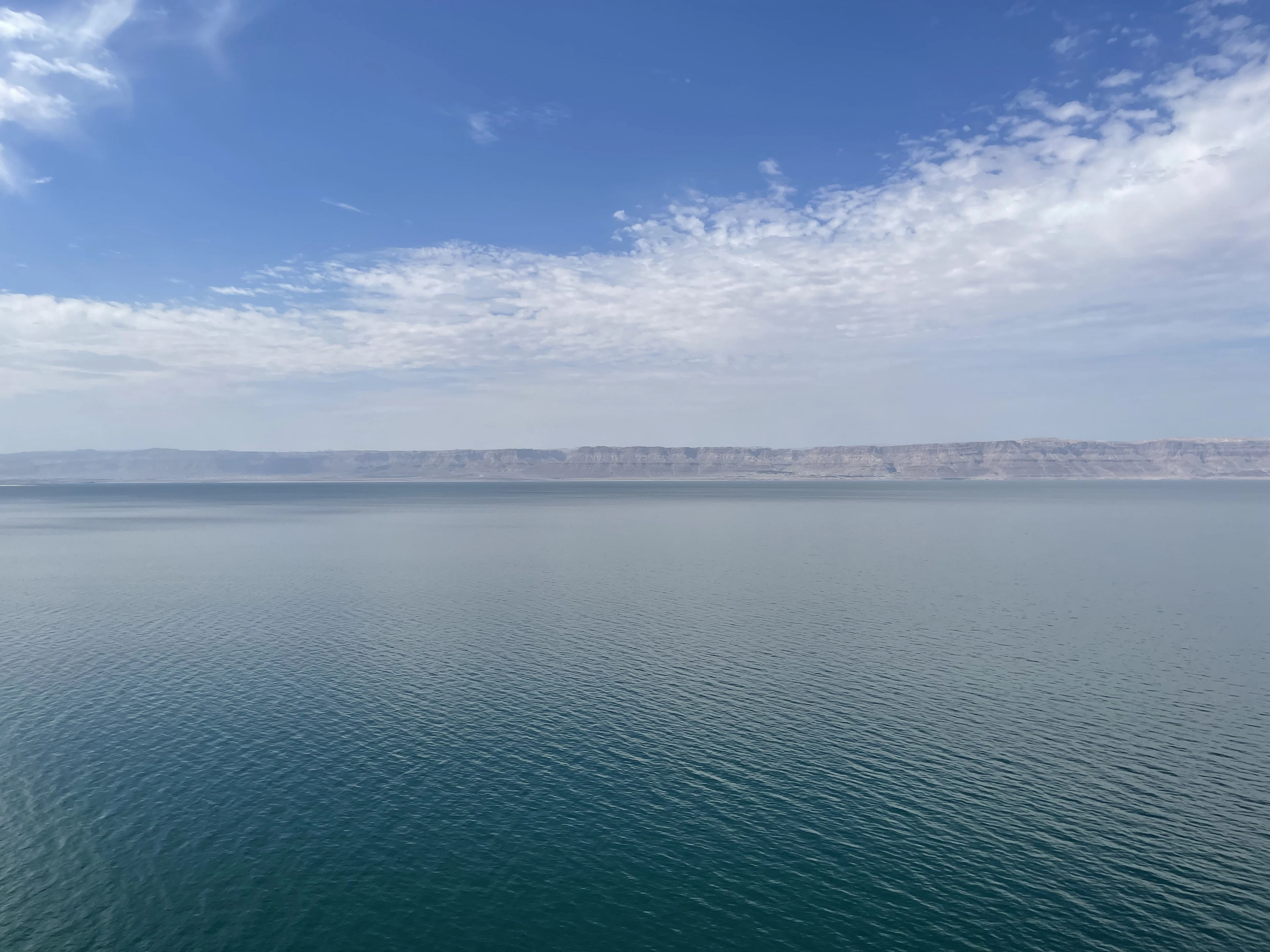 The calm blue expanse of the Dead Sea and a distant shore beneath a pale sky, Jordan