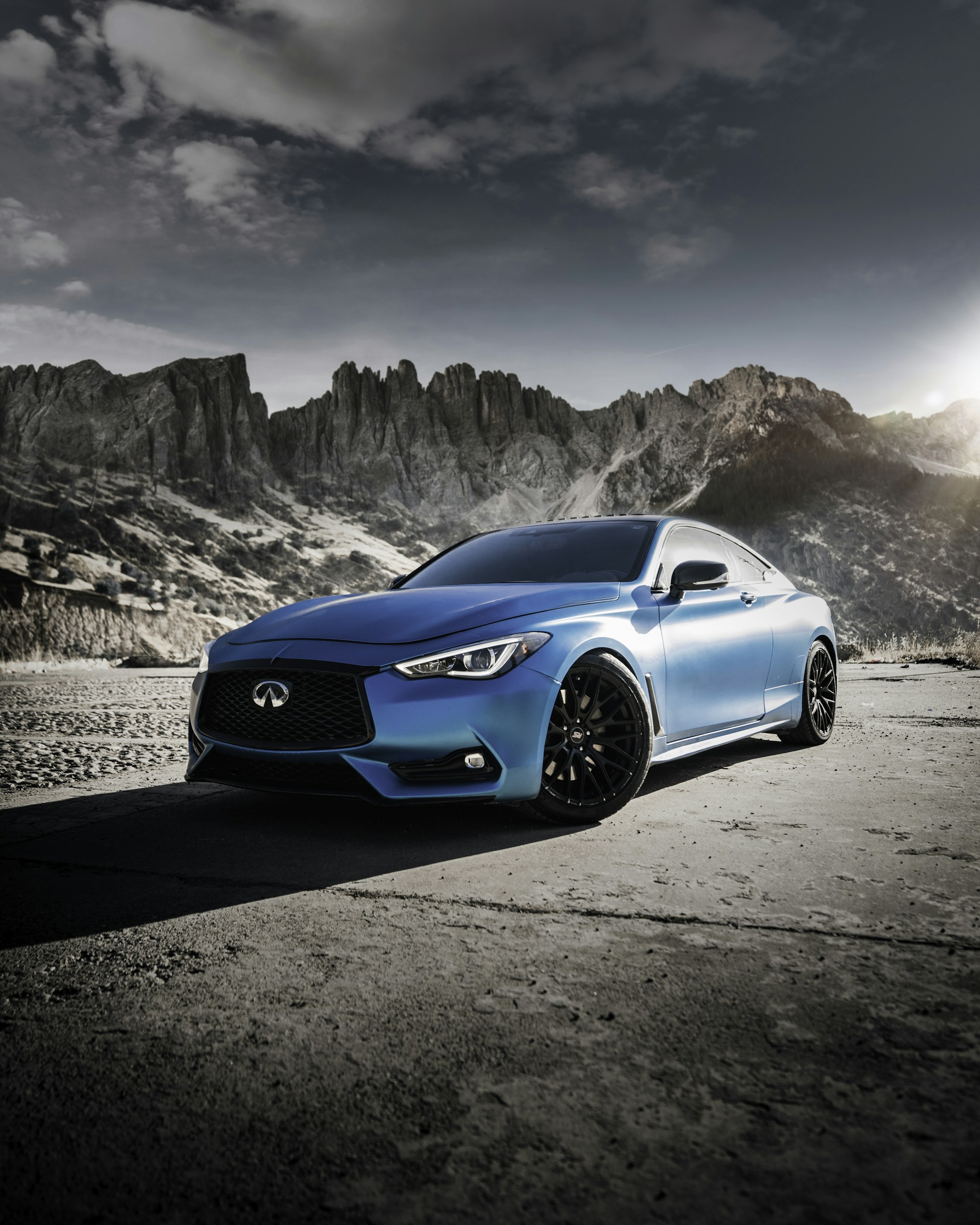 a blue car parked in front of a mountain
