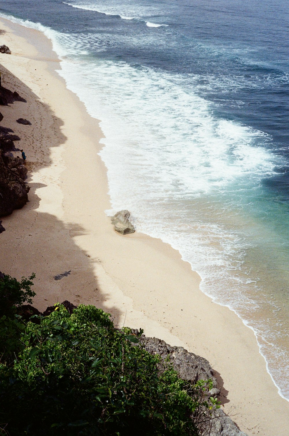 Blick auf einen Strand mit einem großen Felsen im Wasser