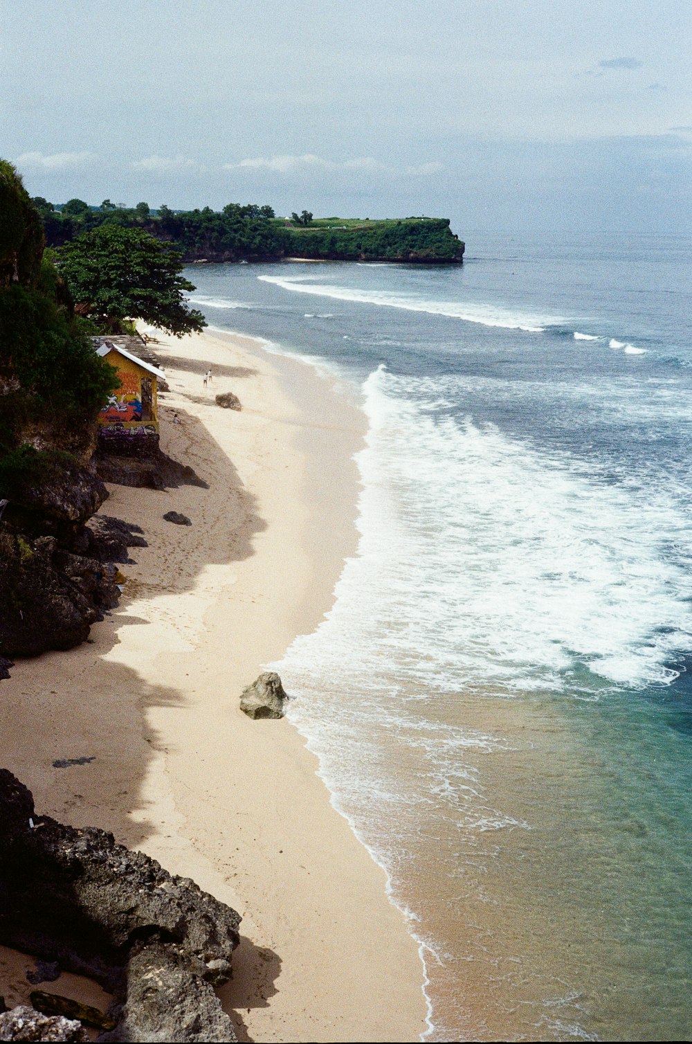 a view of a sandy beach with waves coming in from the ocean