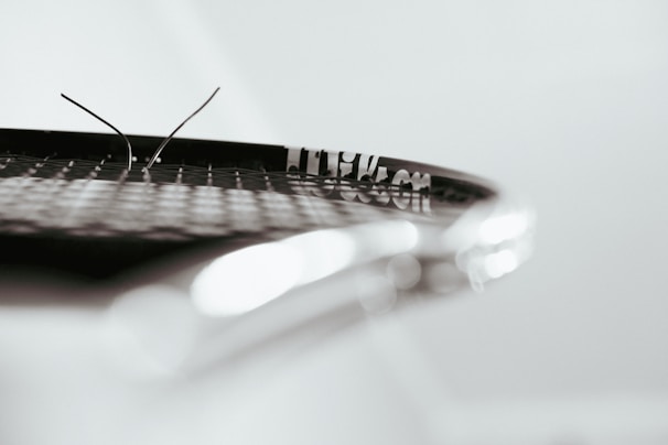 A detailed shot of a worn tennis racket with clay dust on its strings.