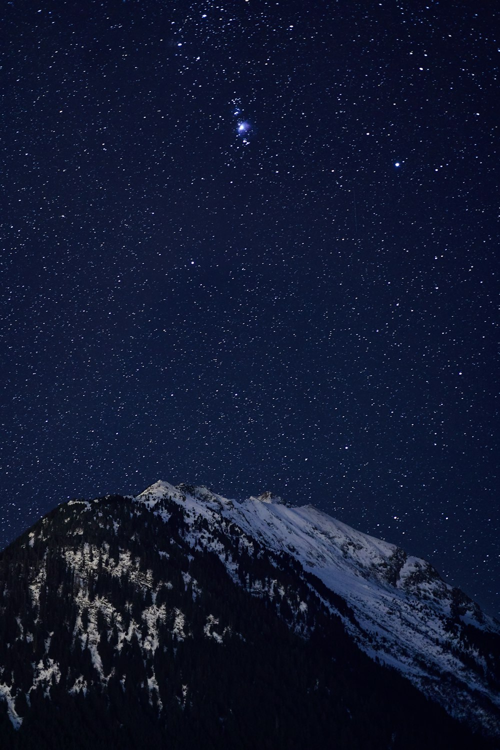 the night sky with stars above a mountain