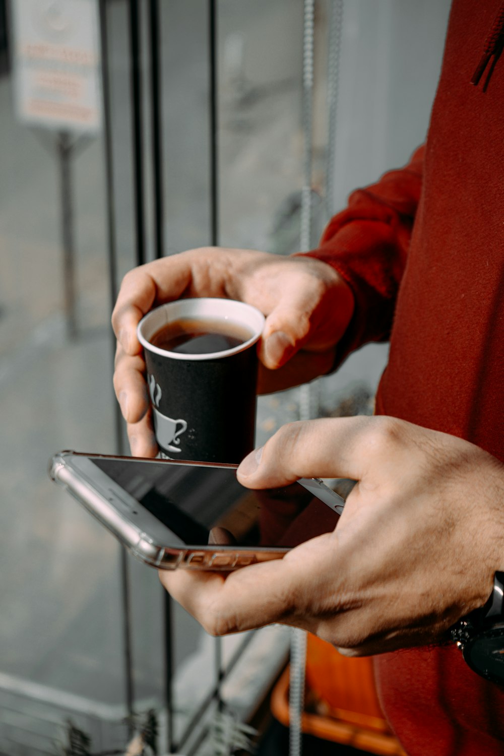 a man holding a cup of coffee and a cell phone