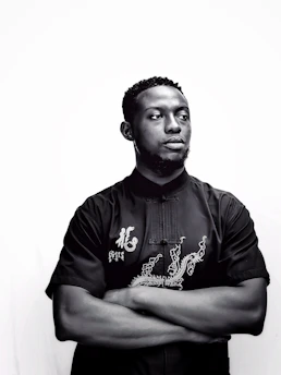 Model wearing a sleek black t-shirt, highlighting the sharp, flawless fit against a dark background.