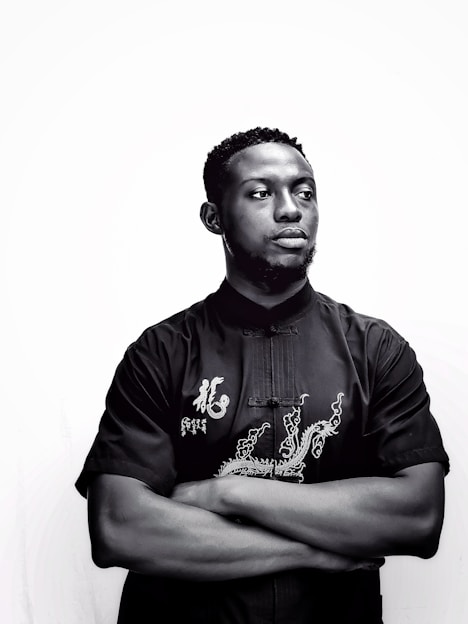 a man with his arms crossed standing in front of a white wall