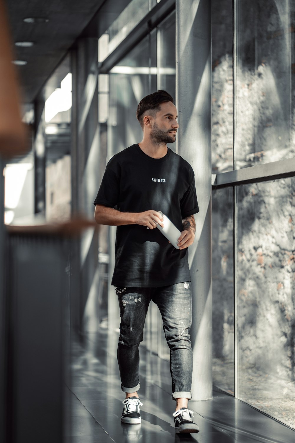 a man in a black shirt is walking down a hallway