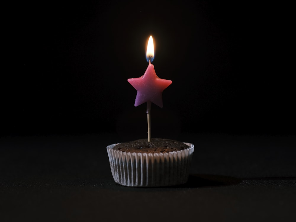 un cupcake con una vela encendida que sobresale de él