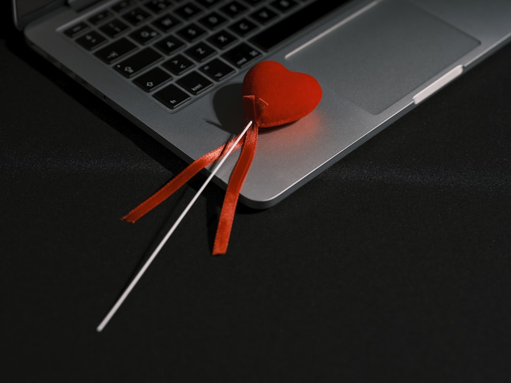 a heart shaped lollipop sitting on top of a laptop computer