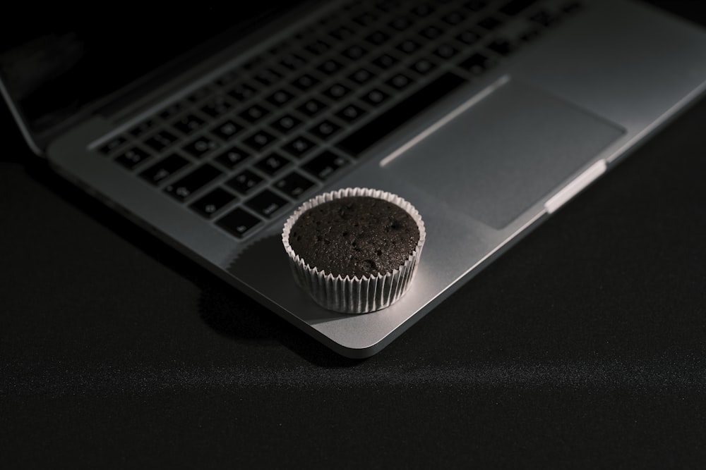 a cupcake sitting on top of a laptop computer