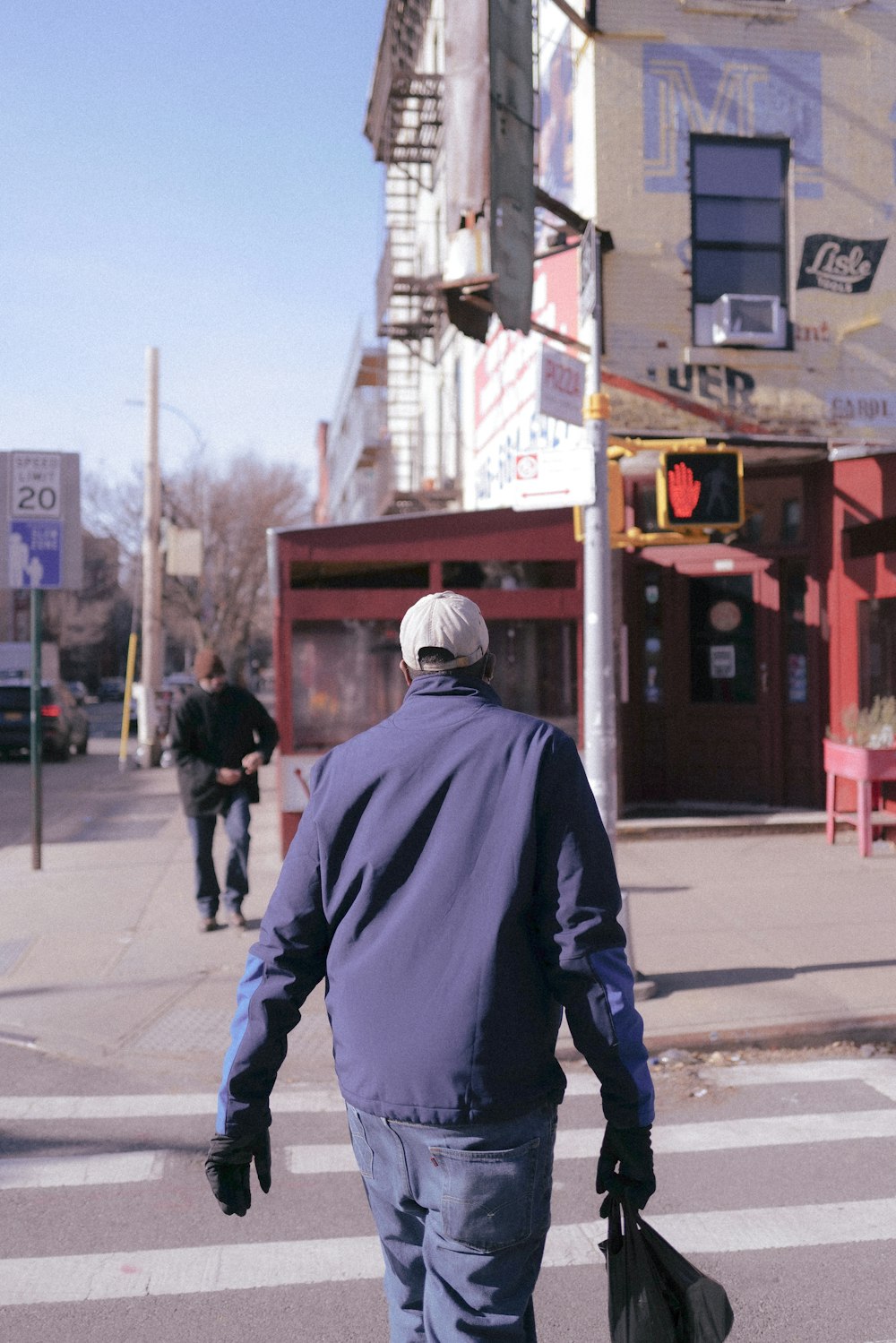 a man walking across a street holding two bags