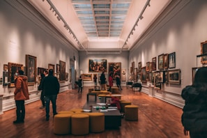 a group of people looking at paintings in a museum