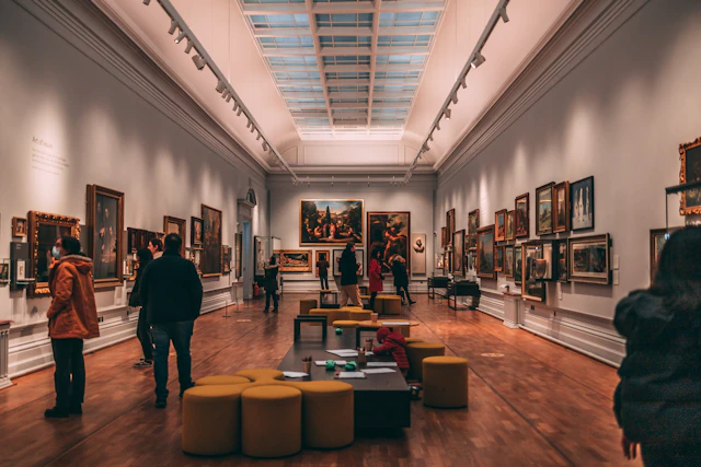 Visitantes recorriendo una galería de arte y observando pinturas