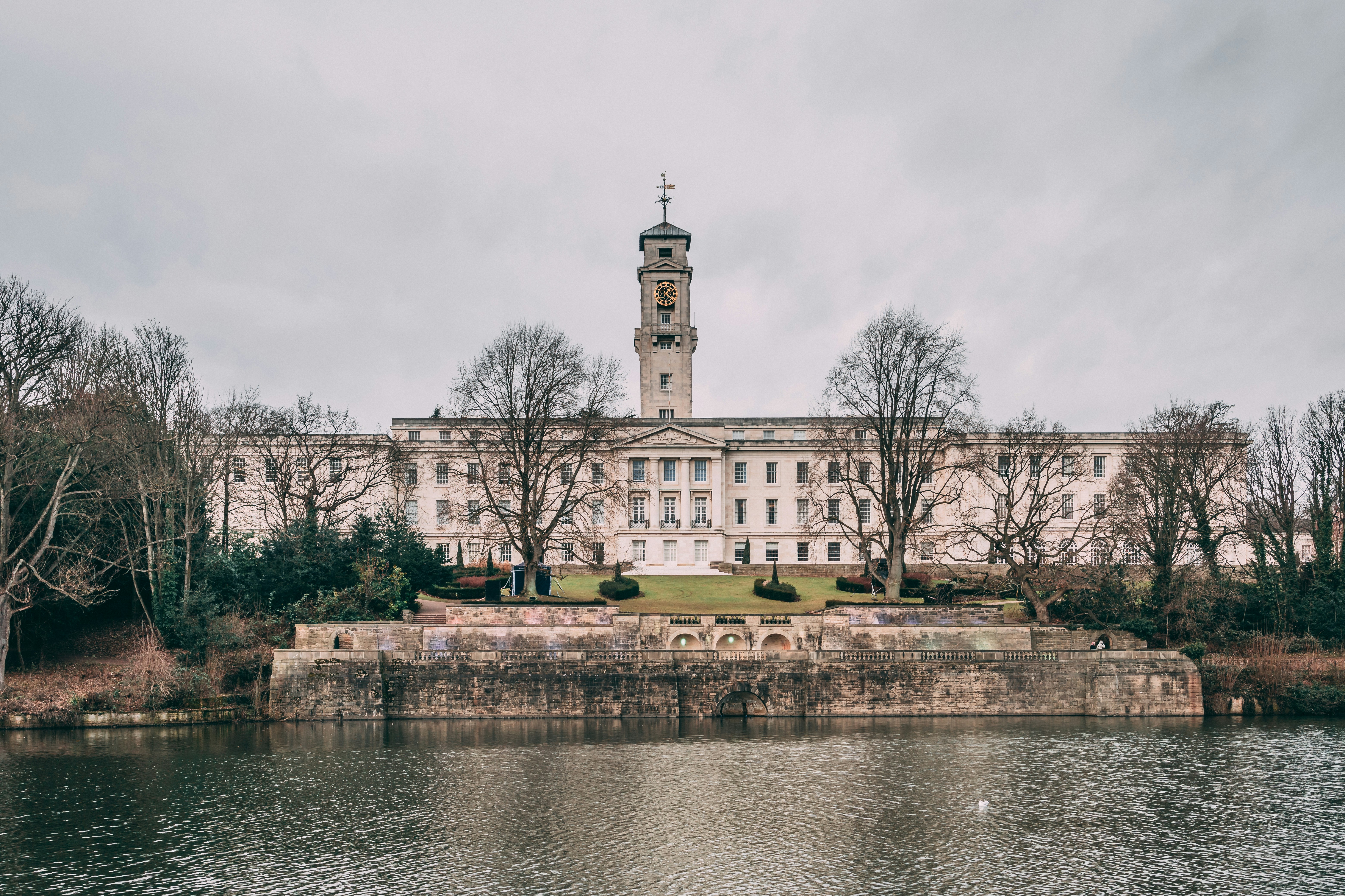 A large building with a clock tower next to a body of water photo