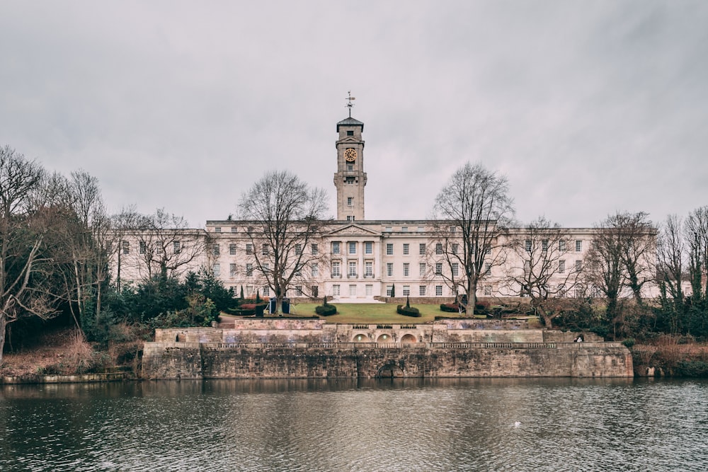 a large building with a clock tower next to a body of water