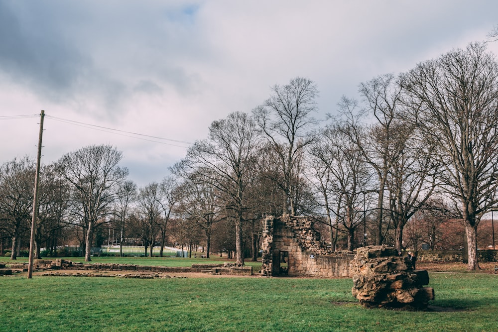 a stone structure in the middle of a grassy field