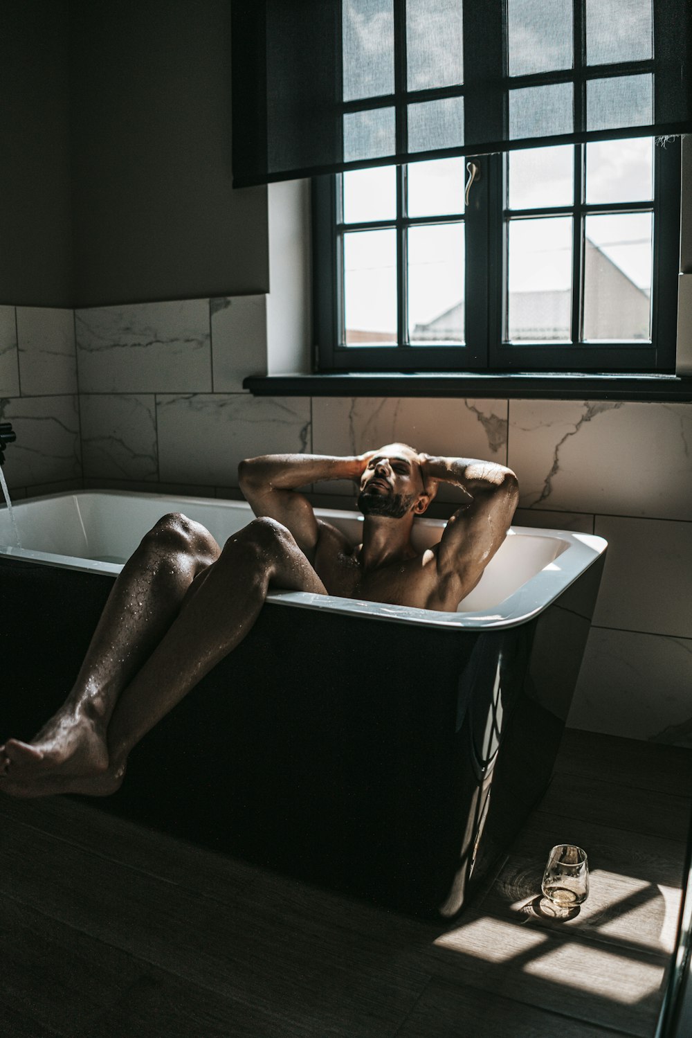 Un hombre desnudo está sentado en una bañera