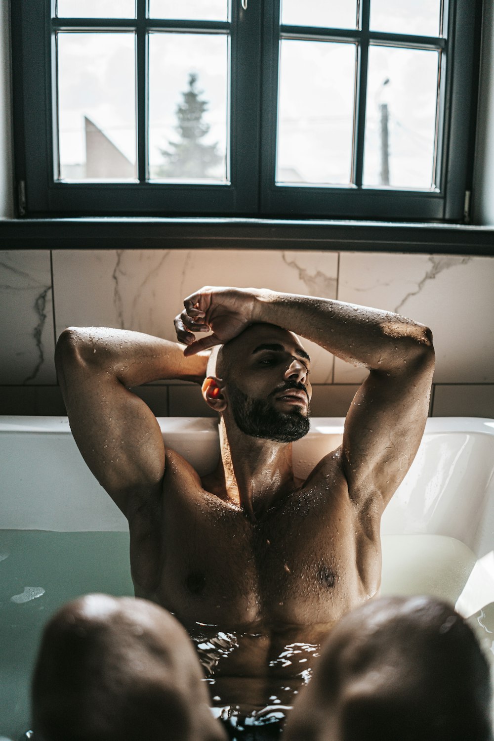 a man sitting in a bathtub with his hands on his head