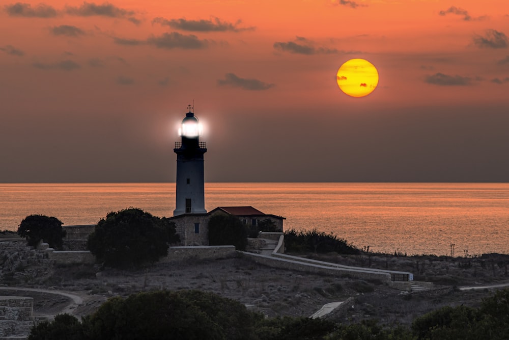 a lighthouse with a bright yellow sun in the background