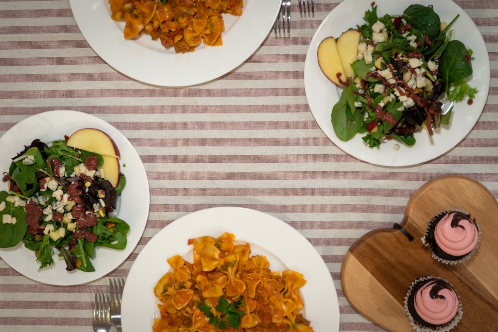 three plates of food on a table with utensils